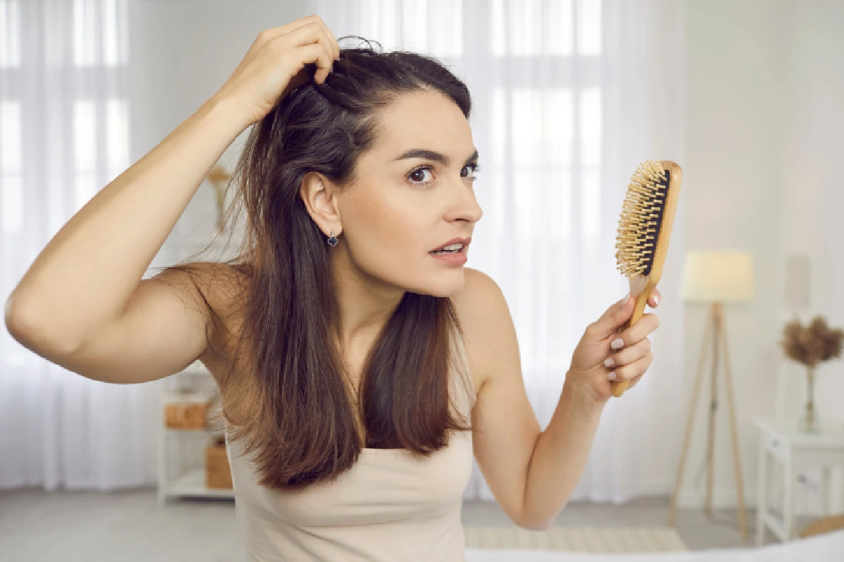 Woman experiencing dry scalp and clogged hair follicles while brushing her hair and looking for HydraFacial Keravive at ARA Med Spa